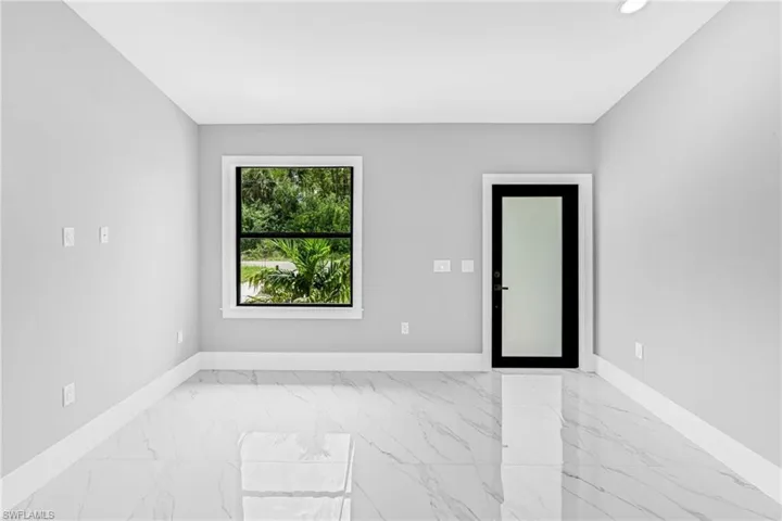 Interior room featuring light gray walls, white baseboards, and polished porcelain tile flooring with a marble-like pattern
