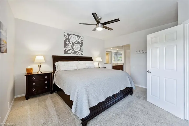Bedroom with ensuite bath, light colored carpet, and ceiling fan