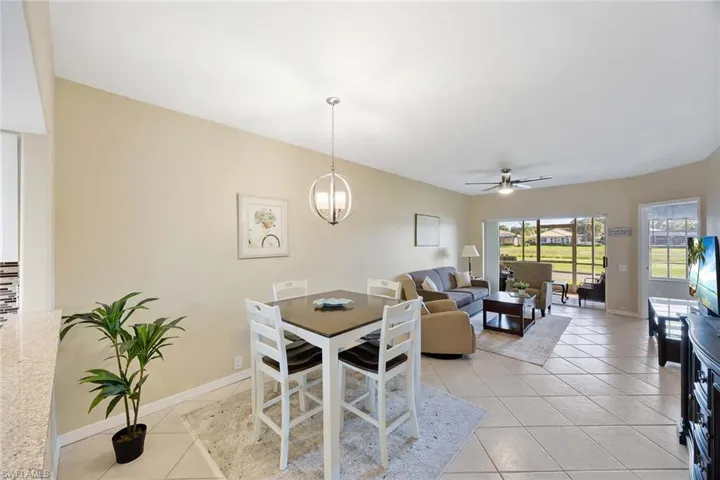 Dining space with a ceiling fan, light tile patterned flooring, and a chandelier