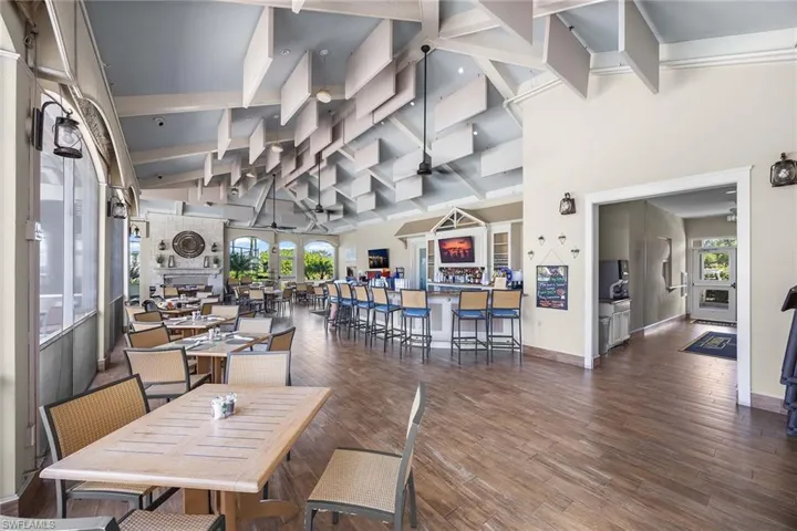 Dining room featuring high vaulted ceiling, dark wood-style floors, beam ceiling, and ceiling fan