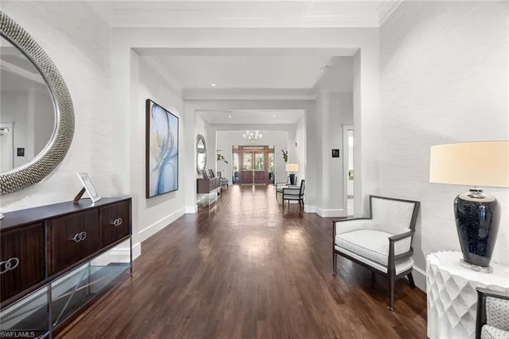 Hallway with dark wood-style floors, crown molding, and a chandelier