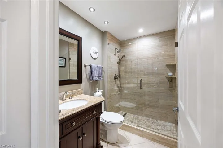 Bathroom featuring vanity, a shower stall, light tile patterned floors, and recessed lighting