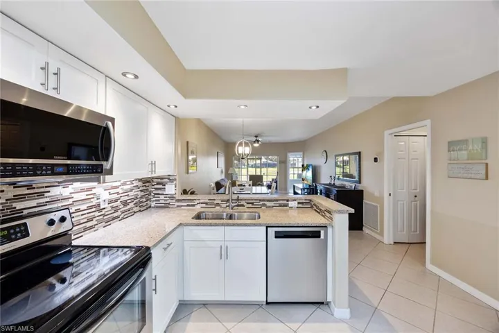 Kitchen with appliances with stainless steel finishes, a peninsula, white cabinets, and recessed lighting