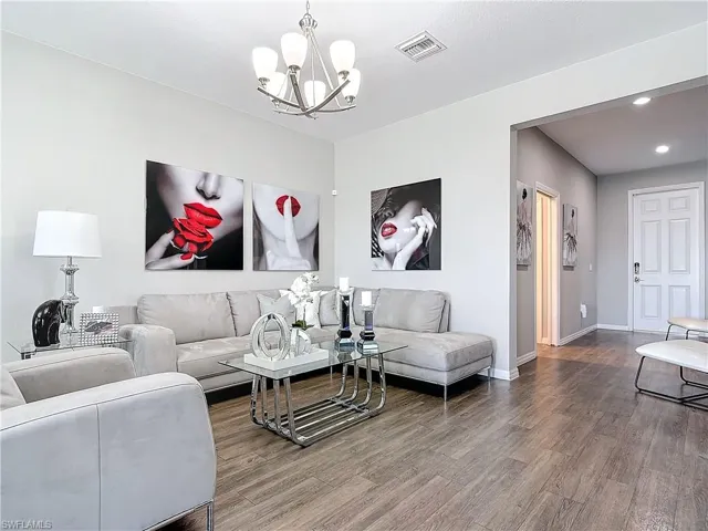 Living area with a notable chandelier, recessed lighting, wood finished floors, visible vents, and baseboards