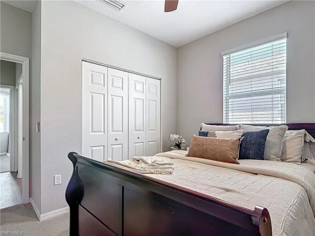 Bedroom featuring light colored carpet, a ceiling fan, baseboards, visible vents, and a closet
