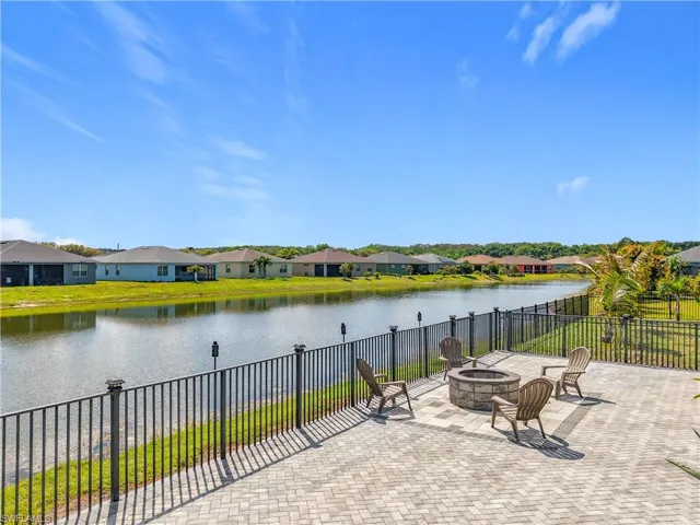 View of patio featuring a fire pit, a water view, fence, and a residential view