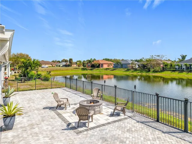 View of patio with a fire pit, a water view, fence, and a residential view