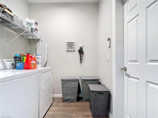Laundry area with laundry area, light wood-type flooring, washing machine and dryer, and baseboards