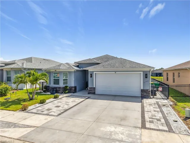 View of front of home featuring a garage, fence, a front lawn, and stucco siding