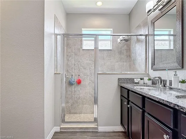 Bathroom featuring a healthy amount of sunlight, a stall shower, a sink, and wood finished floors