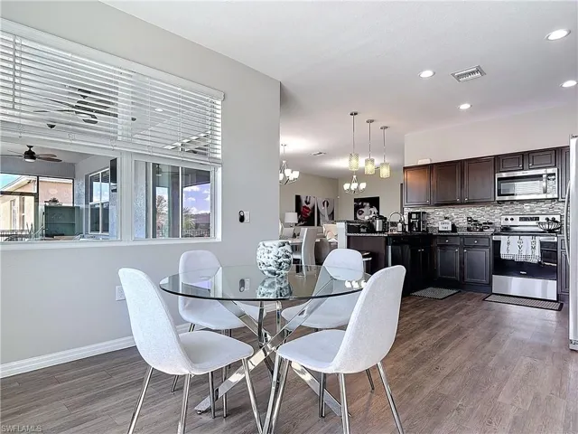Dining area featuring ceiling fan with notable chandelier, dark wood finished floors, visible vents, and recessed lighting