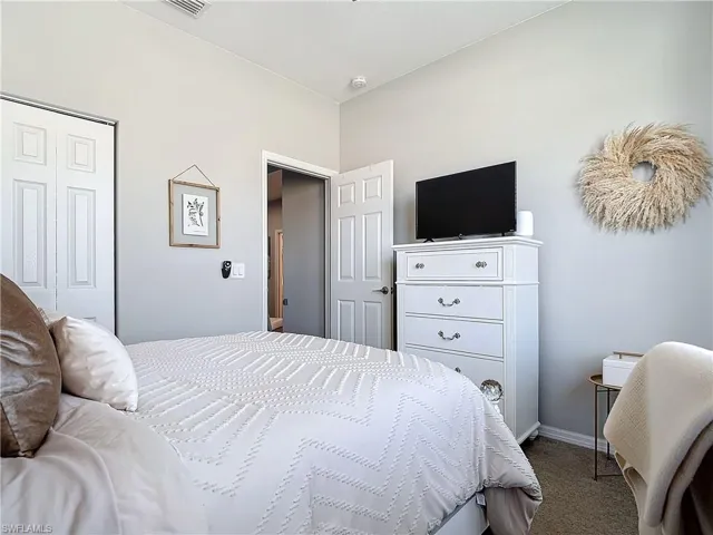 Carpeted bedroom featuring a closet, visible vents, and baseboards
