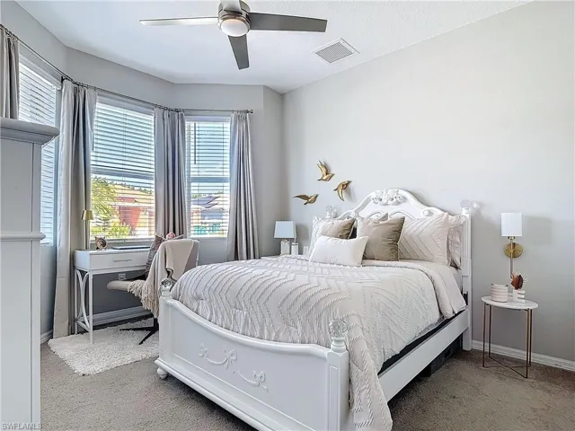 Carpeted bedroom with a ceiling fan, visible vents, and baseboards