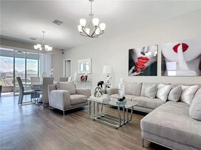 Living room featuring wood finished floors, visible vents, and a notable chandelier