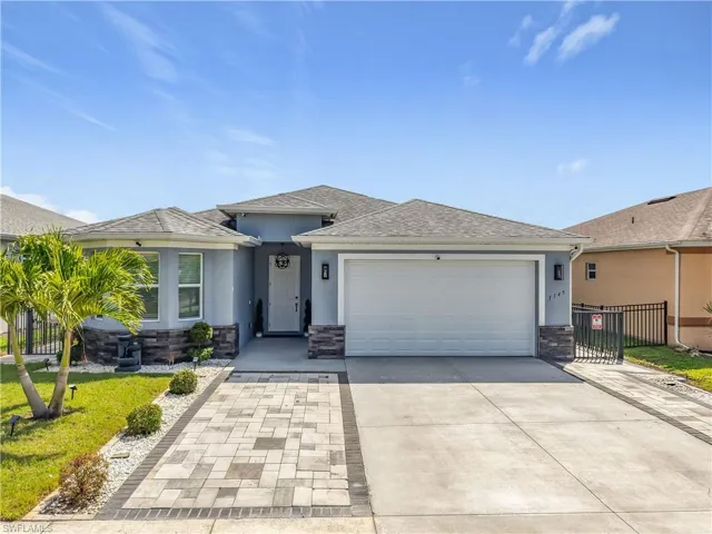 View of front facade featuring stucco siding, concrete driveway, an attached garage, fence, and stone siding