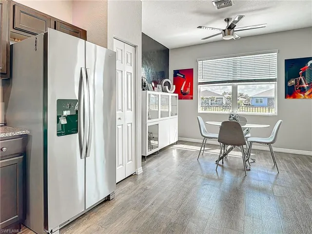 Kitchen featuring dark brown cabinets, light wood-style flooring, stainless steel fridge with ice dispenser, and a textured ceiling