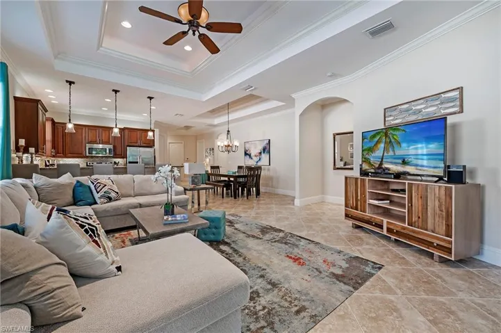 Great Room w/ Porcelain tiled flooring  featuring a raised ceiling, crown molding, and ceiling fan