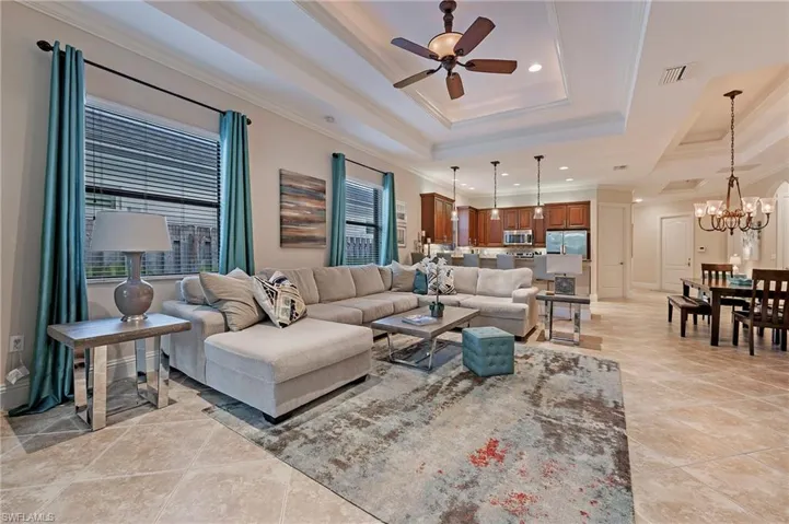 Great Room with a raised ceiling, crown molding, and ceiling fan