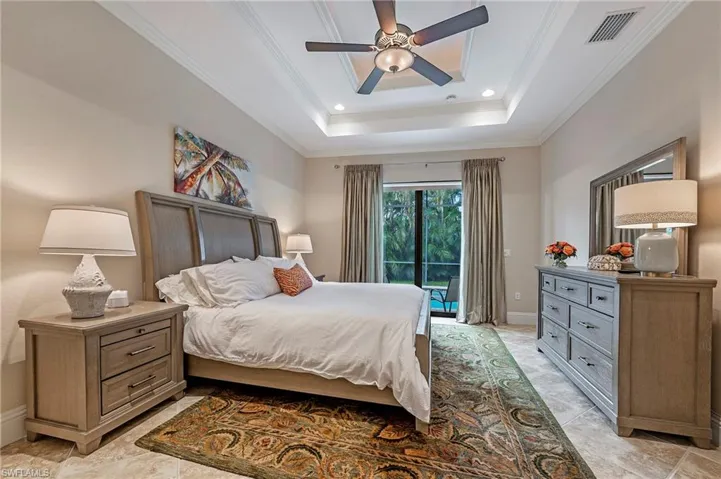 Primary Bedroom featuring crown molding, access to screened pool, and a tray ceiling