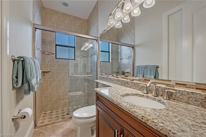Guest Bathroom #3 featuring vanity, porcelain tiled flooring, a shower with shower door, and toilet