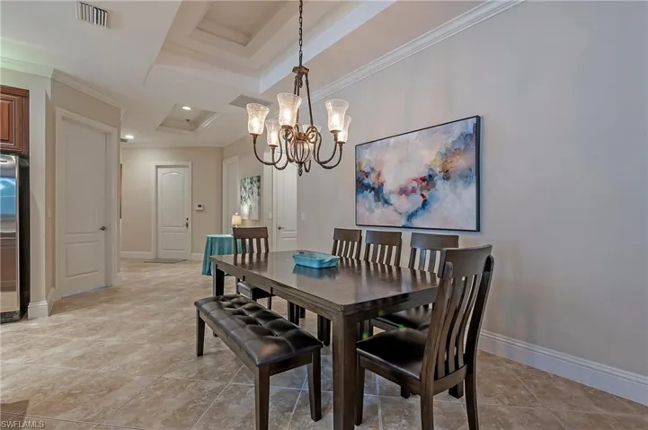 Tiled dining space with an inviting chandelier and crown molding