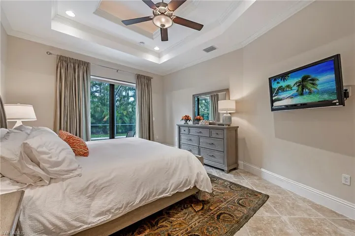 Primary Bedroom featuring crown molding, access to screened pool, and a tray ceiling