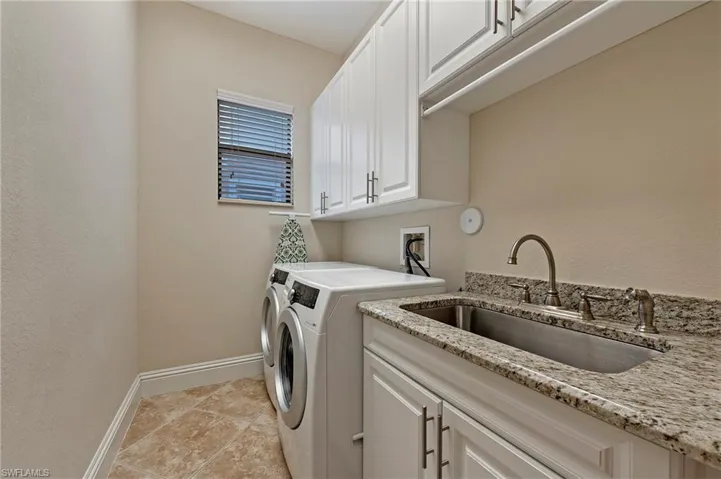 Laundry room with cabinets, washing machine and dryer, sink, and porcelain tiled flooring