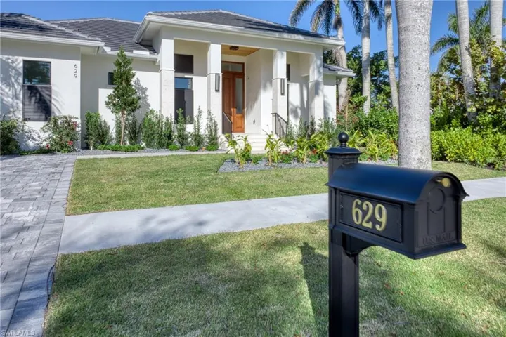 View of front facade featuring stucco siding, a front yard, and a tiled roof