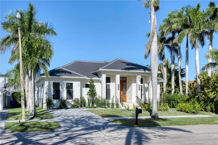 View of front of house with a tiled roof, stucco siding, driveway, and a front yard