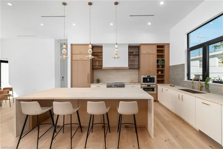 Kitchen featuring a large island, modern cabinets, open shelves, a sink, and range