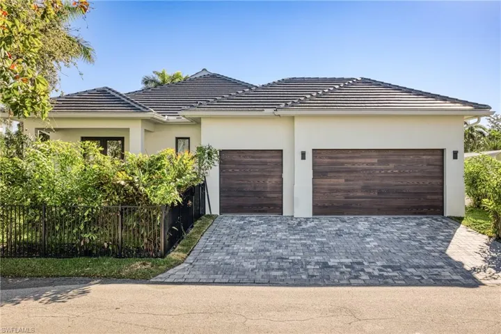 View of front of house with stucco siding, decorative driveway, an attached garage, and fence