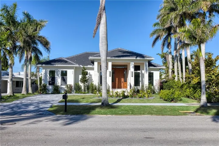 View of front of property with stucco siding, driveway, and a front lawn