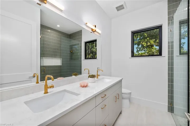 Full bath featuring a shower stall, toilet, visible vents, and a sink