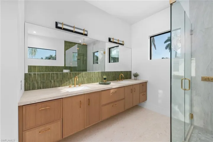 Bathroom with double vanity, backsplash, a stall shower, and a sink