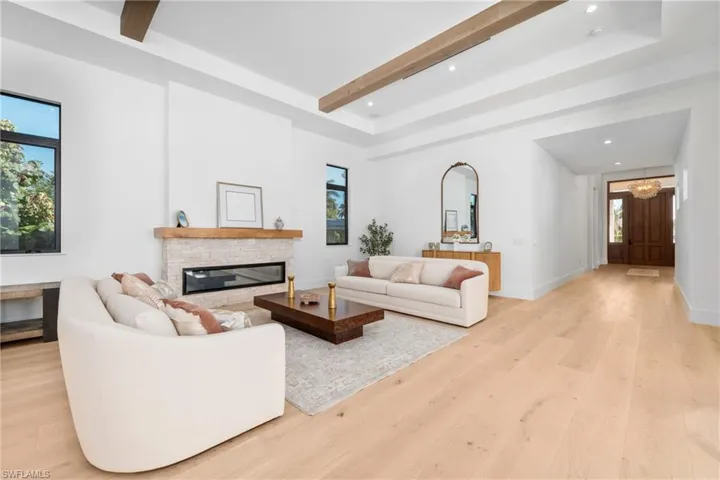 Living area featuring baseboards, beam ceiling, recessed lighting, a fireplace, and light wood-style floors