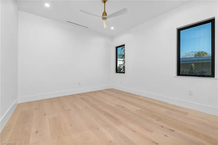 Empty room featuring a ceiling fan, recessed lighting, baseboards, and light wood finished floors