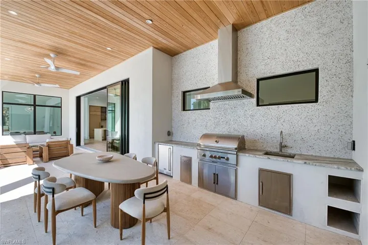 View of patio featuring outdoor dining space, a ceiling fan, a sink, grilling area, and an outdoor kitchen