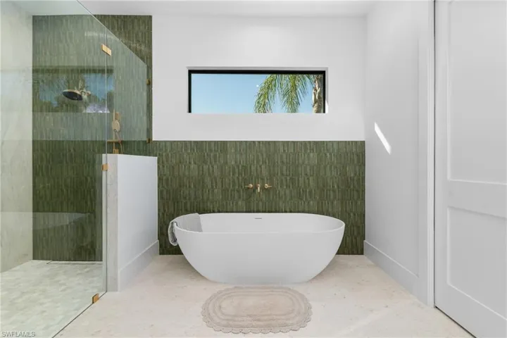Bathroom featuring tile walls, walk in shower, and a freestanding tub