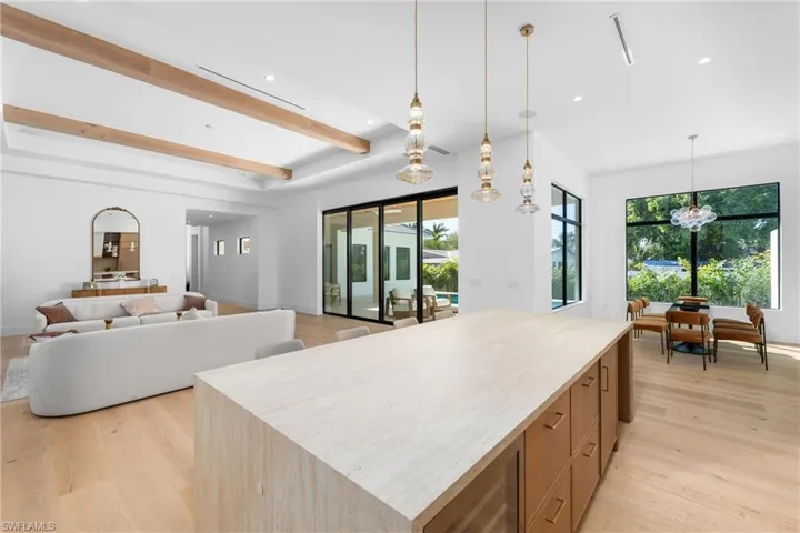 Kitchen with light wood-style flooring, a healthy amount of sunlight, beamed ceiling, and a spacious island