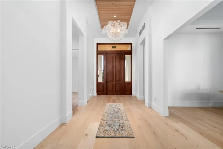 Foyer entrance featuring baseboards, wood finished floors, wood ceiling, and a chandelier