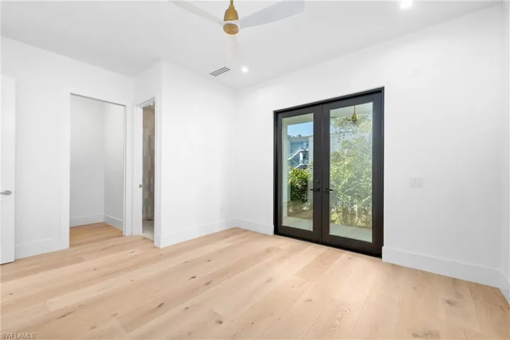 Empty room with visible vents, french doors, baseboards, and wood finished floors