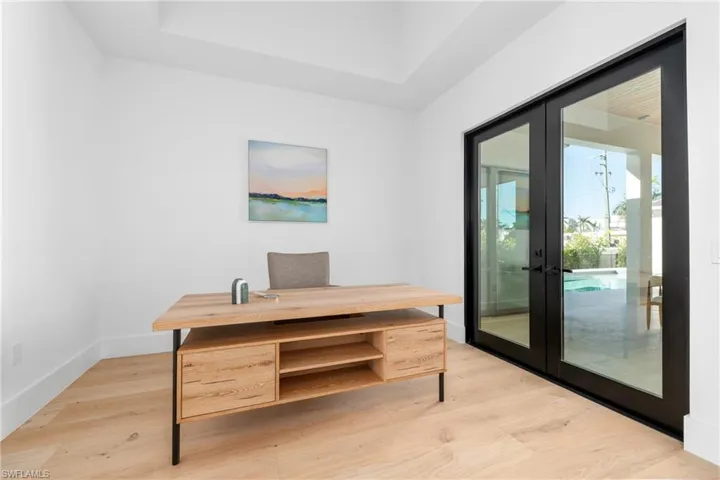 Office area with light wood-style flooring, french doors, and baseboards