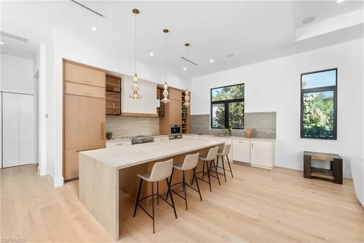 Kitchen with tasteful backsplash, a kitchen island, light wood-style flooring, and light countertops