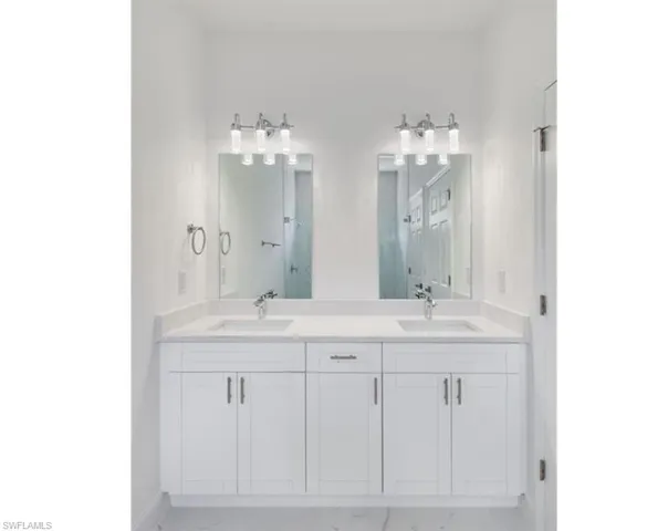 Dual vanity featuring white shaker-style cabinetry, undermount sinks, and stone countertops