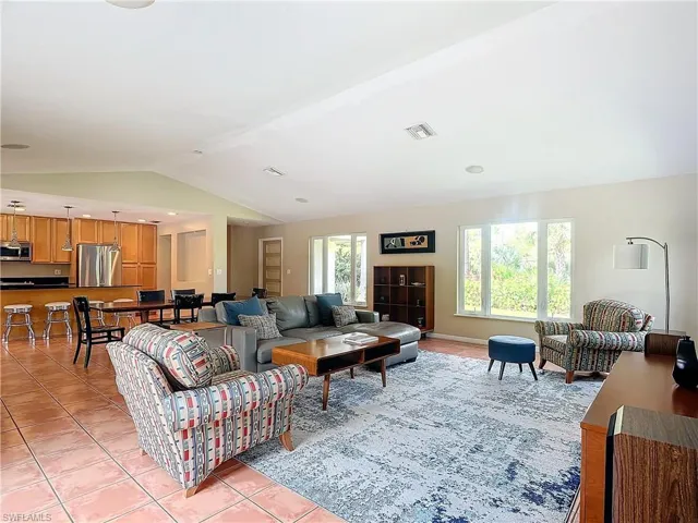 Living room with a wealth of natural light, lofted ceiling, and tile floors