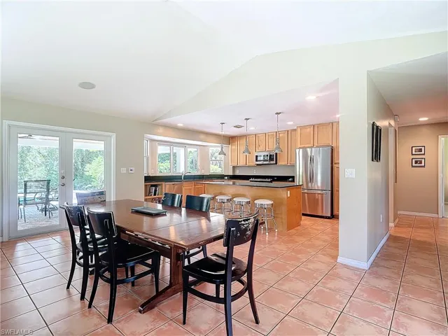 Tiled dining space with lofted ceiling and French doors to covered Veranda