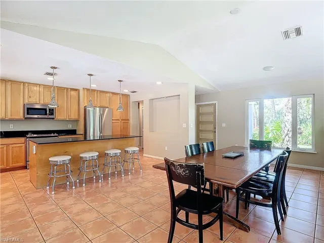 Tiled dining area featuring vaulted ceiling