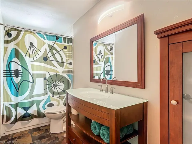 Full guest bathroom with shower / tub combo, vanity, window and toilet
