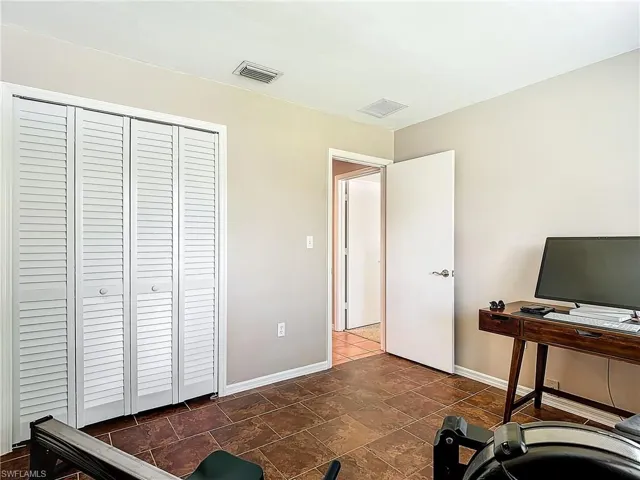 Guest bedroom with large window and closet. Currently set up as office/workout space.