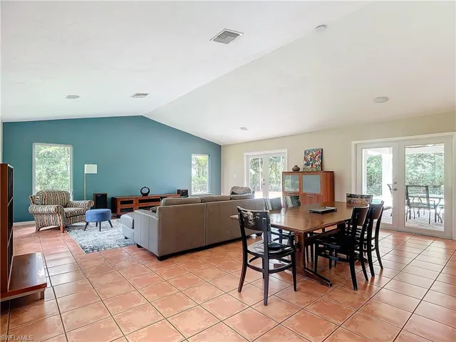 Dining area with french doors leading to lanai, lofted ceiling, plenty of natural light, and tile floors